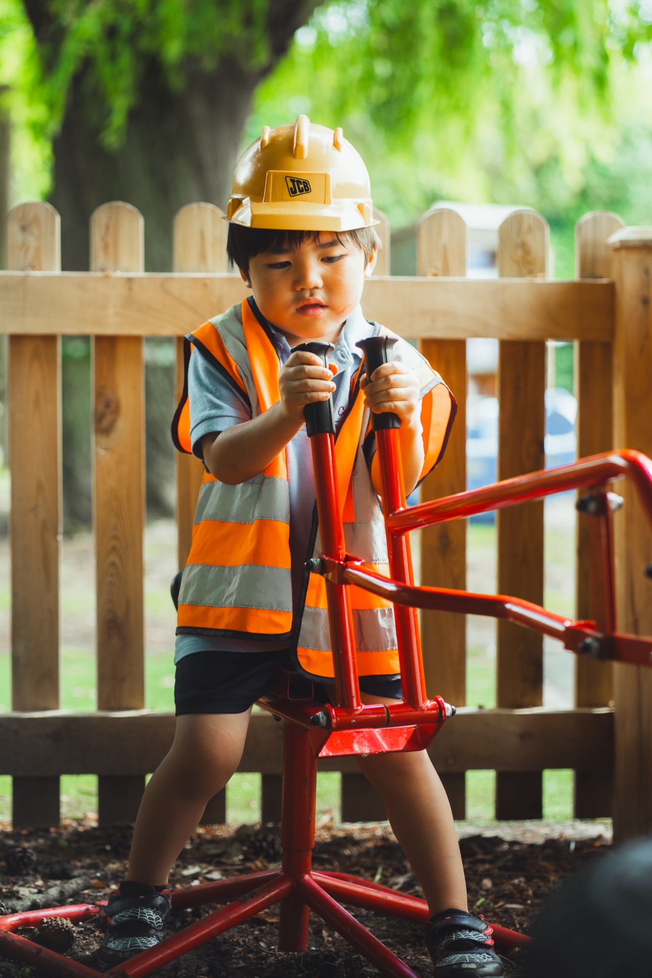 student wearing JCB hard hat on toy digger